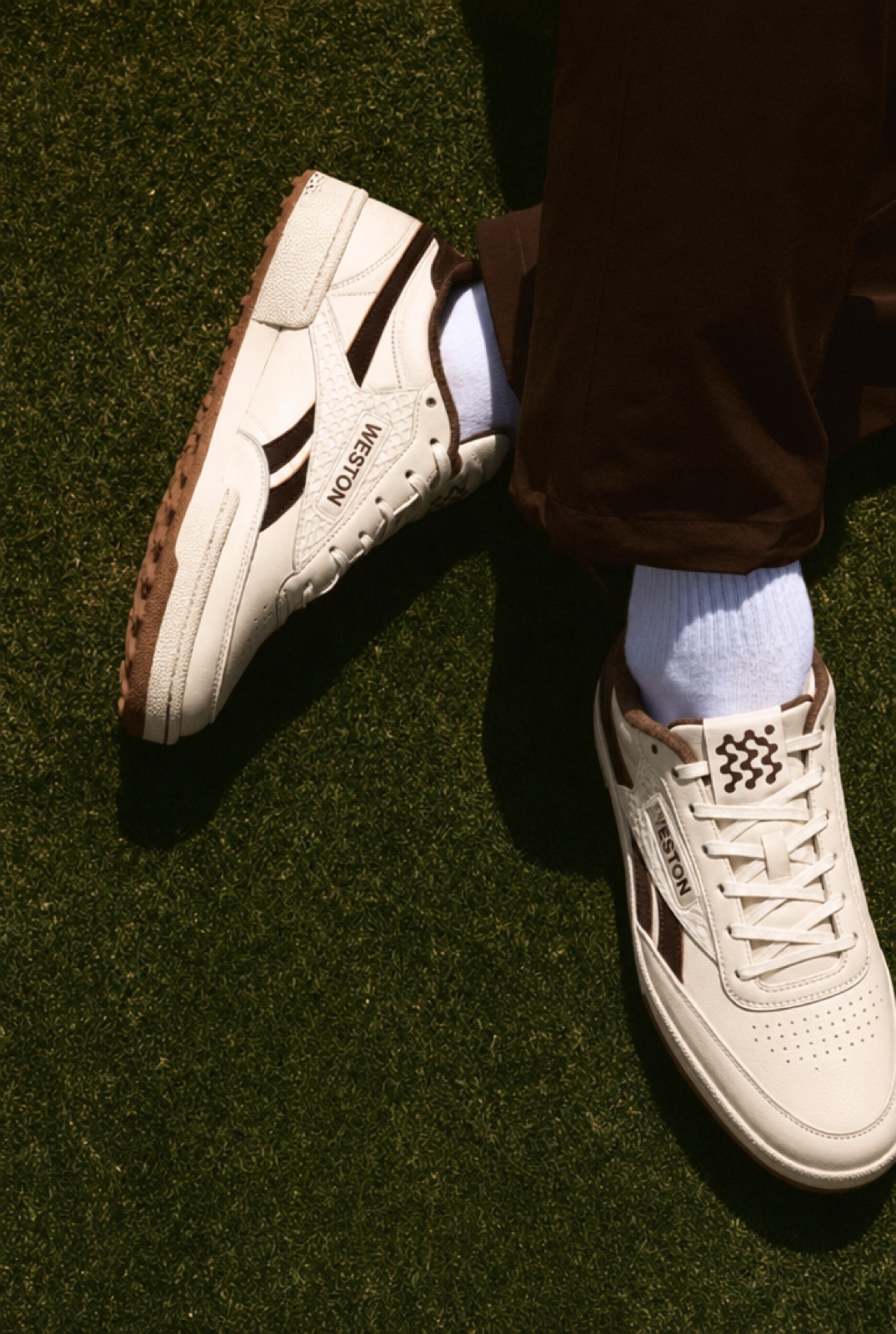 Both shoes from above in Espresso, crossed on the fairway grass.
